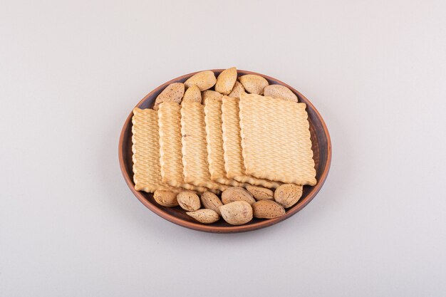 Plato de almendras orgánicas sin cáscara y galletas sobre fondo blanco. Foto de alta calidad