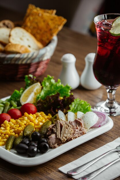 plato de aperitivos con aceituna, maíz, ternera hervida, lechuga, cornichon, tomate, limón