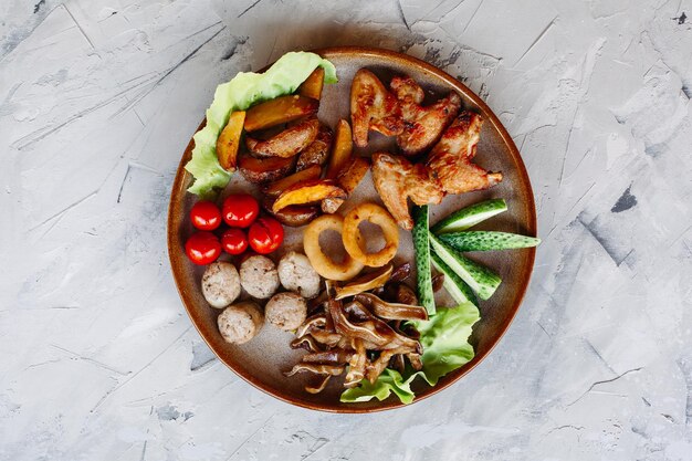 Plato de arcilla lleno de aperitivos, incluidos nuggets de pollo dorados con corteza crujiente, deliciosos canapés con arenque y tomates cherry servidos con salsa de ajo decorada con hojas de ensalada y queso