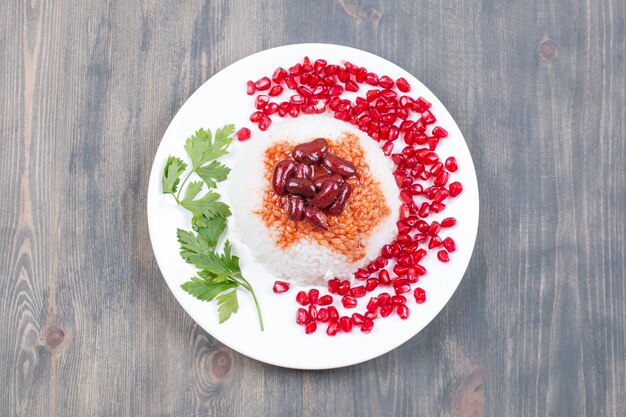 Plato de arroz al vapor con semillas de granada sobre superficie de madera