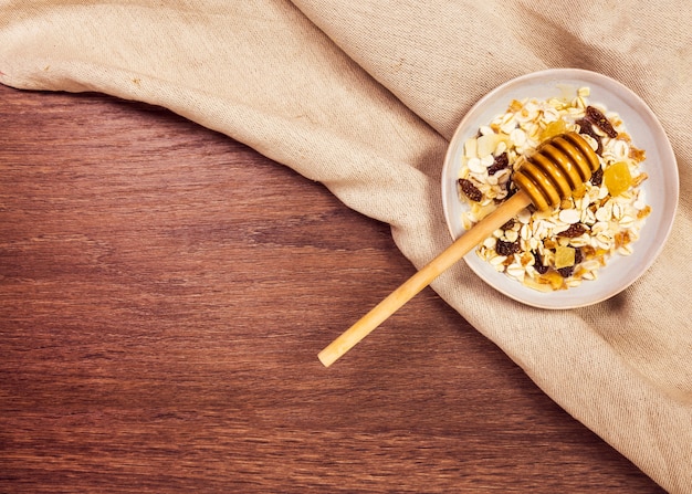 Plato con avena saludable y miel sobre escritorio de madera