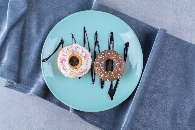 Un plato azul de dos rosquillas dulces con chispitas de colores.