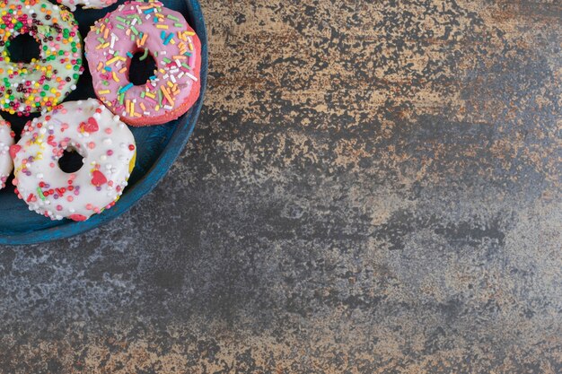 Plato azul con dulces donas espolvoreadas sobre superficie de madera