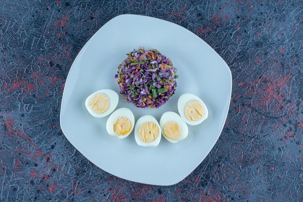 Un plato azul de huevos duros con verduras.