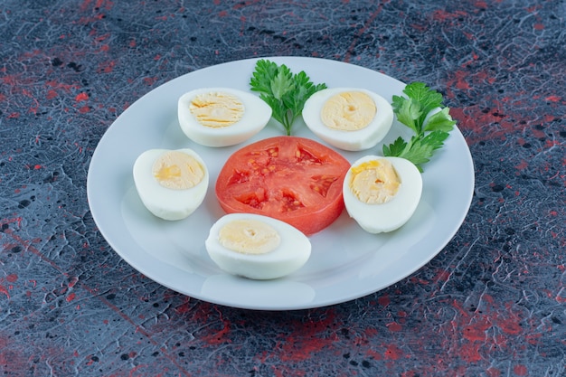 Un plato azul de huevos duros con verduras.