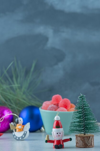 Un plato azul de mermelada con pequeños juguetes festivos navideños sobre fondo de mármol. Foto de alta calidad