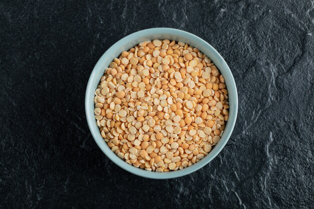 Un plato azul con palomitas de maíz crudas en un oscuro