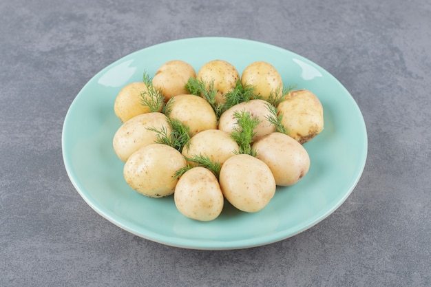 Un plato azul de patatas hervidas con eneldo fresco.