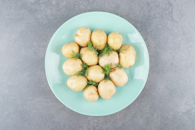 Un plato azul de patatas hervidas con eneldo fresco