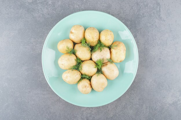 Un plato azul de patatas hervidas con eneldo fresco