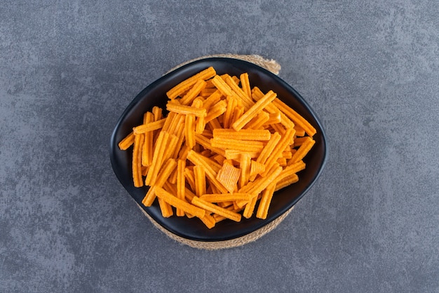 Un plato de batatas fritas en salvamanteles, sobre el fondo de mármol.