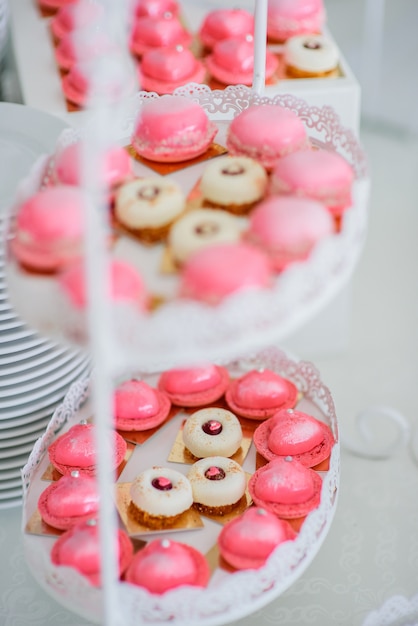 Plato blanco cansado con macarrones rosados ​​y deliciosos pasteles blancos