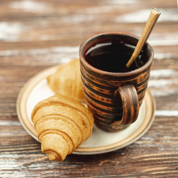 Plato blanco con croissants y taza de café.