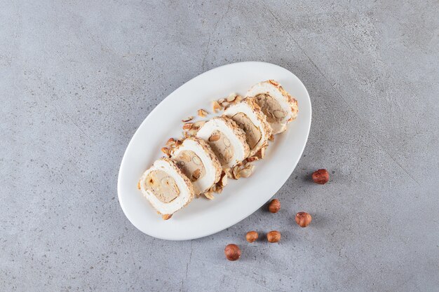 Plato blanco de delicias dulces con frutos secos sobre fondo de piedra.