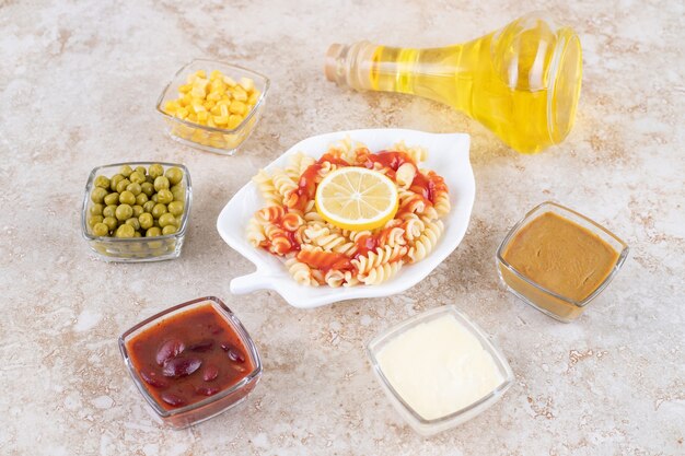 Un plato blanco de deliciosa pasta espiral con rodaja de limón