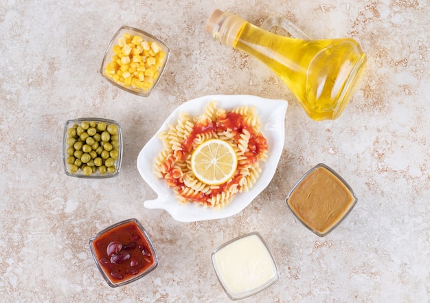 Un plato blanco de deliciosa pasta espiral con rodaja de limón