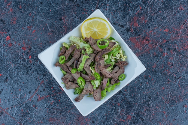 Un plato blanco con deliciosas carnes y hierbas.