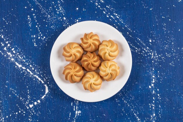 Plato blanco con deliciosas galletas dulces en azul.