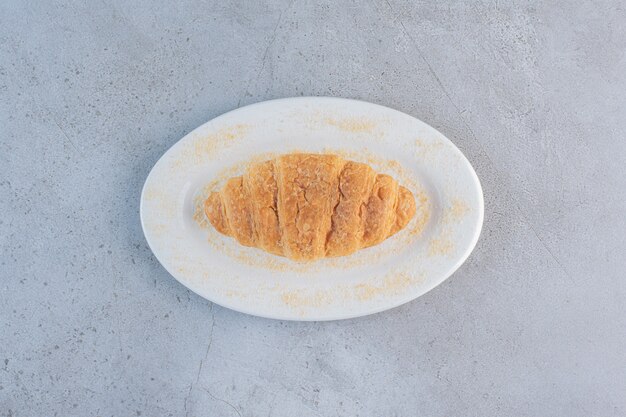 Un plato blanco de delicioso croissant dulce en azul.