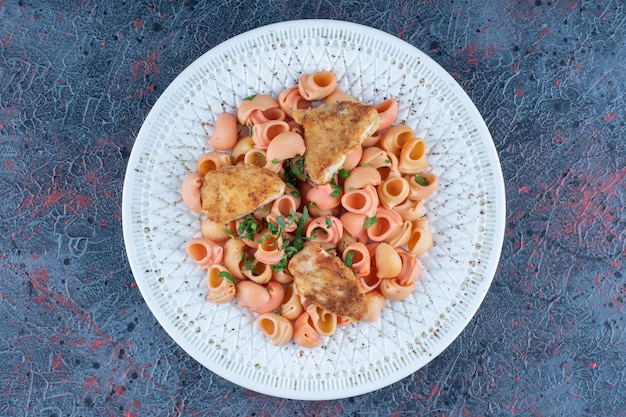 Un plato blanco de deliciosos macarrones con carne de pollo.