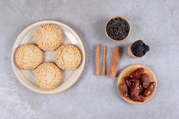 Un plato blanco de galletas dulces y dátiles sobre la superficie de mármol