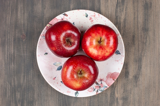 Un plato blanco con jugosas manzanas rojas sobre una mesa de madera. Foto de alta calidad