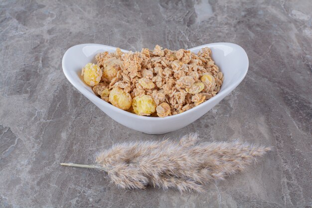 Un plato blanco lleno de deliciosas hojuelas de maíz saludables en la mesa gris.