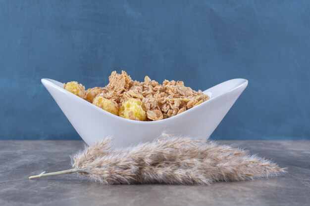 Un plato blanco lleno de deliciosas hojuelas de maíz saludables en la mesa gris.