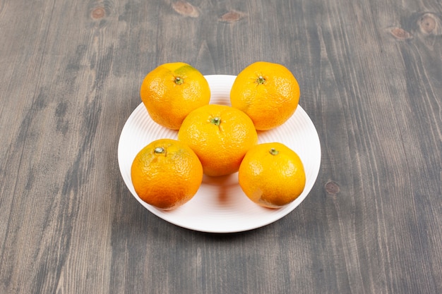 Un plato blanco lleno de dulces mandarinas frescas. Foto de alta calidad