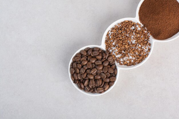 Un plato blanco lleno de granos de café y cacao en polvo.