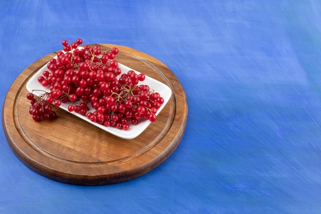 Un plato blanco lleno de grosella roja sobre superficie azul