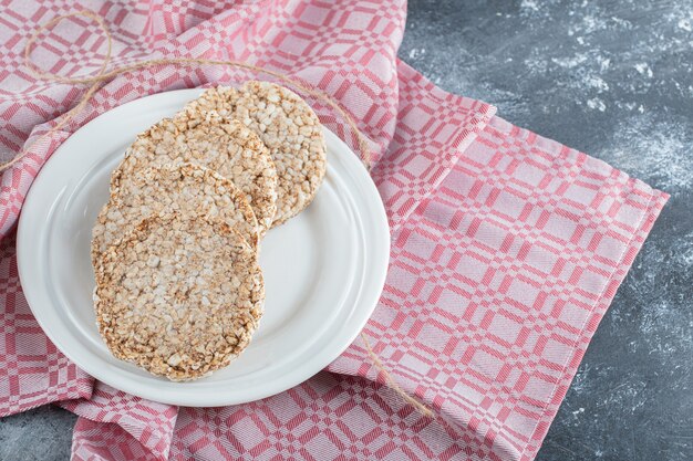 Un plato blanco lleno de pan de arroz inflado sobre un mantel.