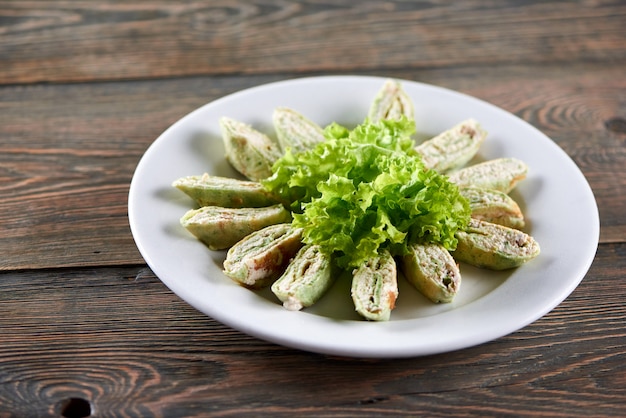 Foto gratuita plato blanco lleno de pita armenia con requesón y verduras. aperitivo decorado con hojas de lechuga. foto hecha en la mesa de madera.