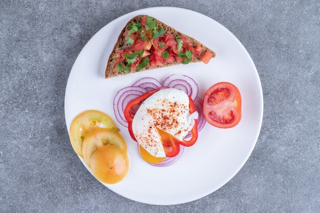 Un plato blanco lleno de verduras en rodajas y huevo cocido. Foto de alta calidad