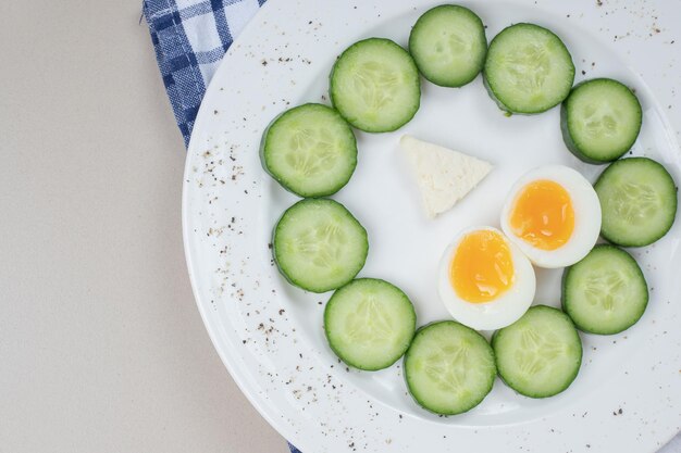 Un plato blanco de pepino en rodajas y huevo cocido.