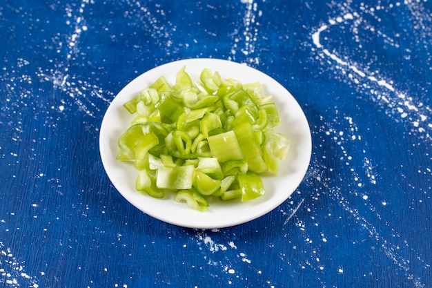 Foto gratuita plato blanco de pimientos verdes en rodajas sobre la superficie de mármol