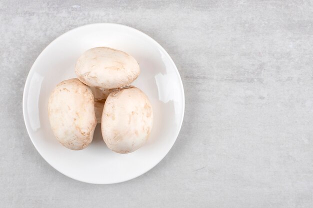 Plato blanco de setas grandes frescas en la mesa de piedra.