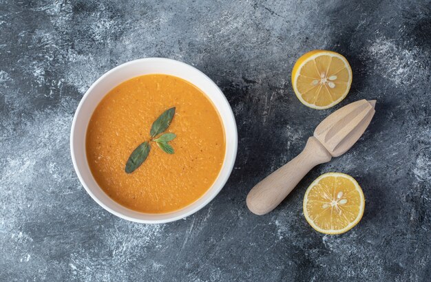 Un plato blanco de sopa de lentejas con rodajas de limón.