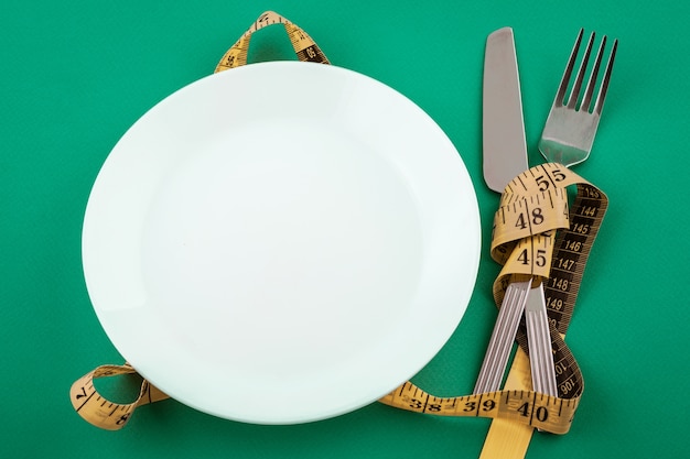 Plato blanco vacío con cinta métrica, concepto de pérdida de peso