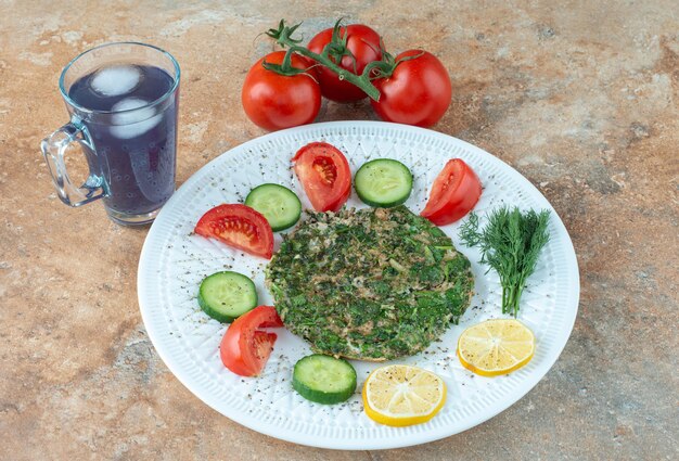 Un plato blanco con verduras y una taza de jugo.