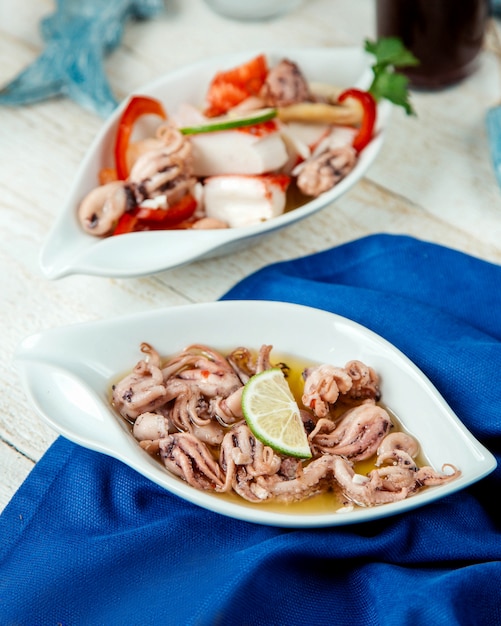 Plato de calamares con limón servido en mesa blanca