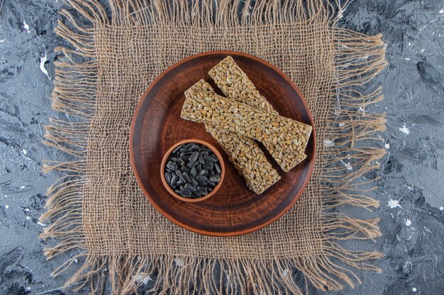 Plato de caramelos quebradizos con semillas de girasol sobre superficie de mármol.