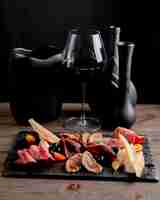 Foto gratuita plato de carne con aceitunas y tomates servidos con copa de vino