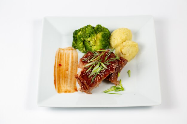 Plato de carne con puré de patatas con salsa barbacoa y brócoli