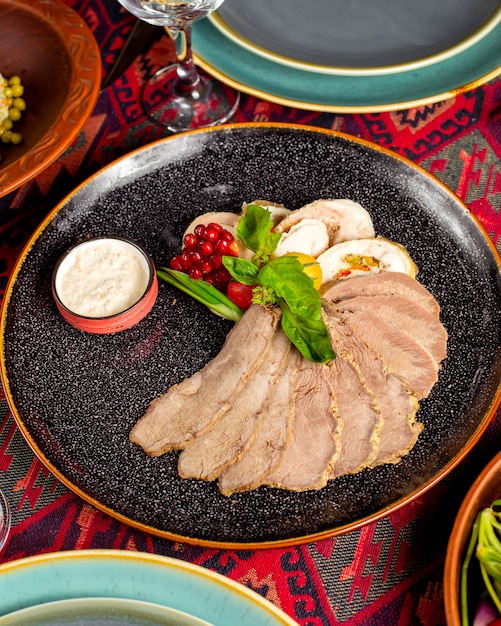 Un plato de carne con rodajas de carne y paté adornado con granada y hierbas