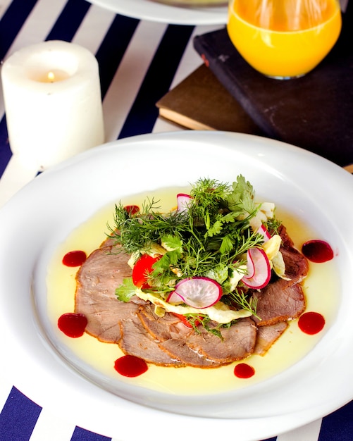 Plato de carpaccio con carne, rábano, lechuga y hierbas