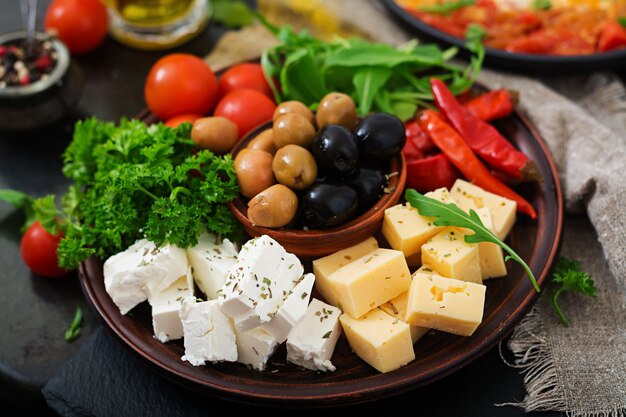 Plato de cena con aceitunas, queso y verduras.