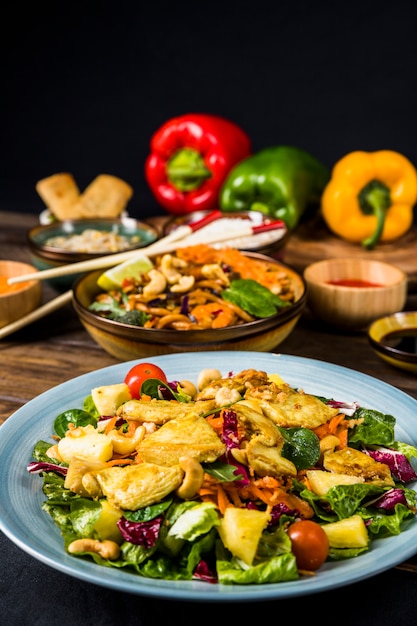 Plato de cerámica de ensalada de pollo con fideos en escritorio