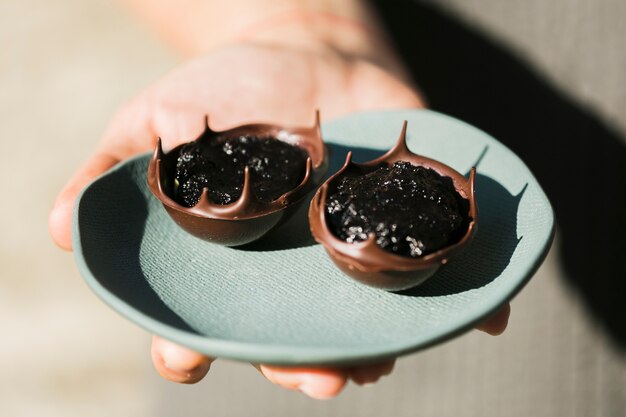 Plato de cerámica de la mano de la persona con delicioso postre de chocolate