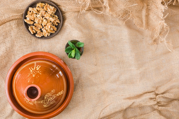 Foto gratuita plato cerca de copa y nueces sobre arpillera.